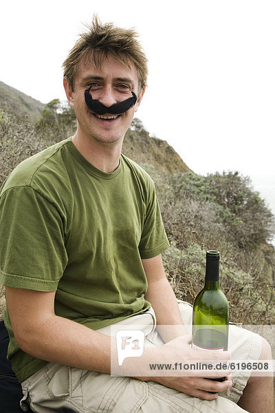 Caucasian man in costume mustache holding wine bottle