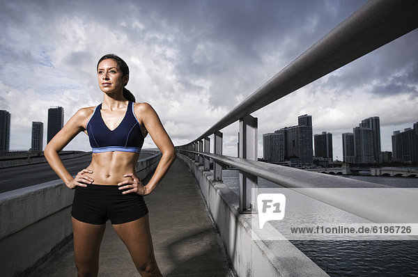 Hispanic woman in sportswear standing near urban waterfront
