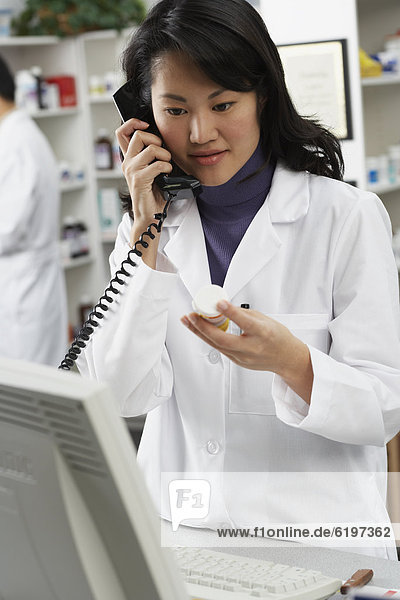 Asian female pharmacist talking on telephone