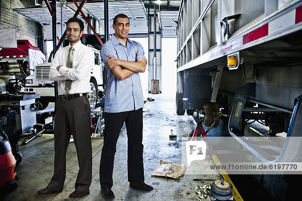 Manager and mechanic standing in auto repair shop