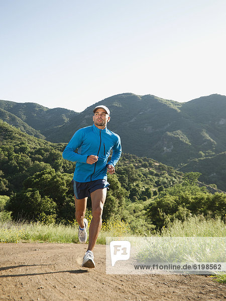 Mixed race man running on remote trail