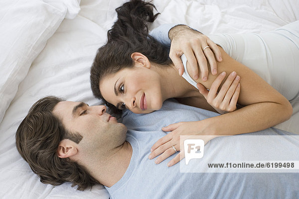 High angle view of Hispanic couple hugging in bed
