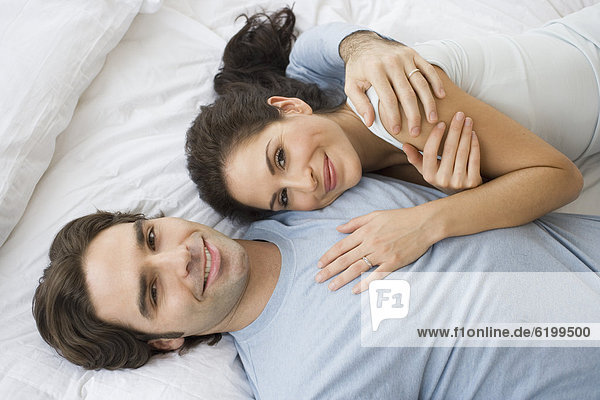 High angle view of Hispanic couple hugging in bed