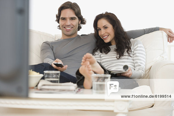 Hispanic couple watching television on sofa