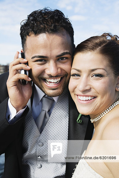 Multi-ethnic bride and groom with cell phone