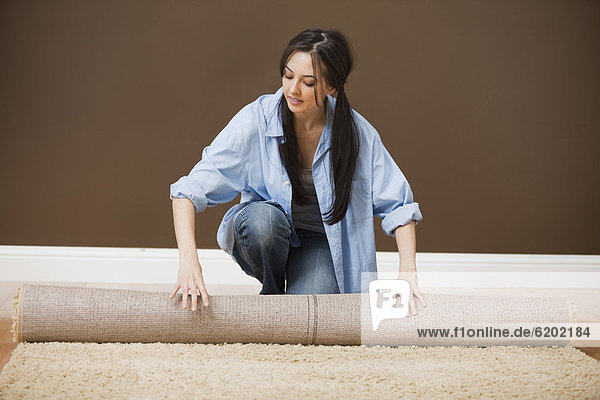 Caucasian woman unrolling carpet