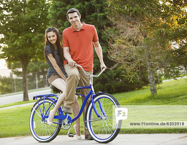 Caucasian couple riding bicycle together