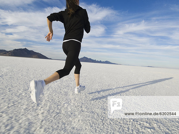 Hispanic woman jogging on salt flats