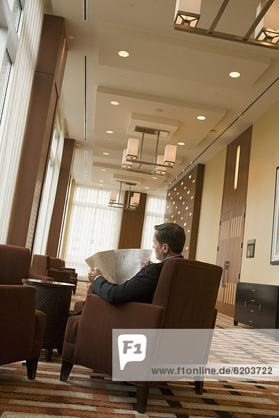 Businessman reading newspaper in lobby