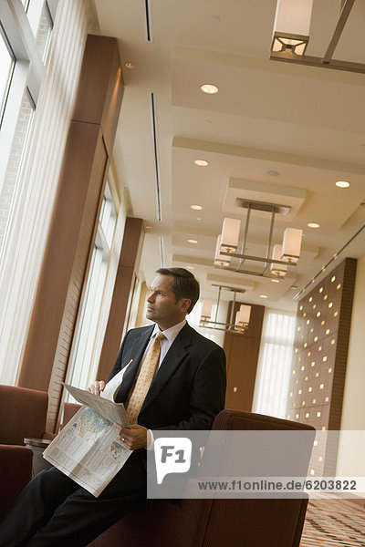 Businessman holding newspaper in lobby