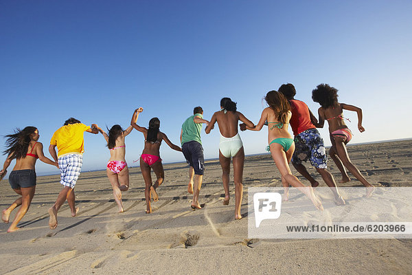 Multi-ethnic group of friends running on beach