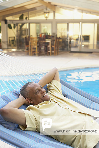 African man laying in hammock at poolside