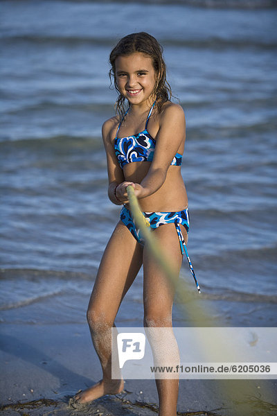Hispanic girl playing tug-of-war on beach