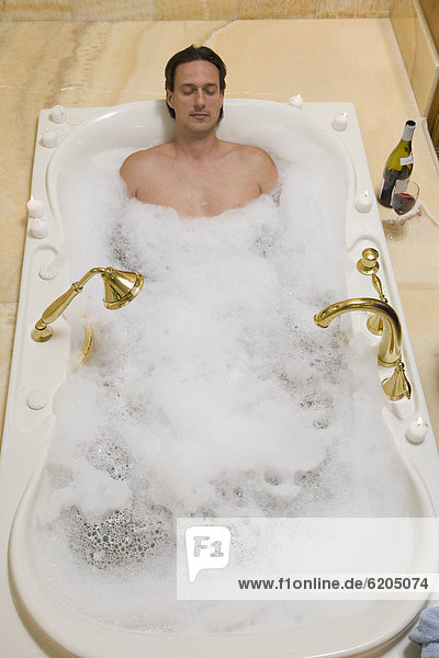 Hispanic man relaxing in bubble bath