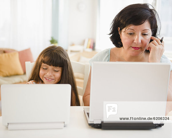 Hispanic mother and daughter using laptops