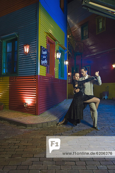 Hispanic couple performing tango on city street