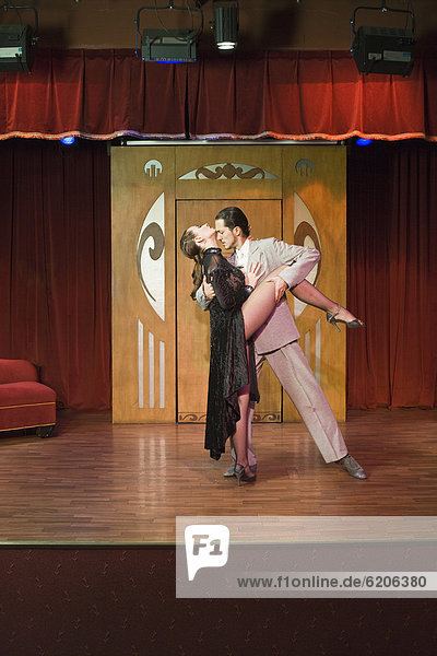 Hispanic couple performing tango on stage