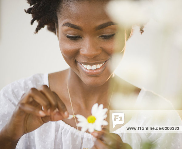 Black woman plucking petals from daisy