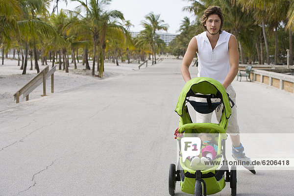 Hispanic man on roller blades pushing jogging stroller