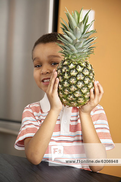 Mixed race boy holding pineapple