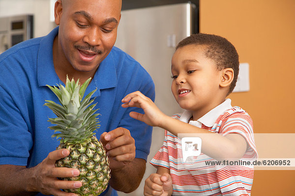 Antiguan father showing pineapple to son
