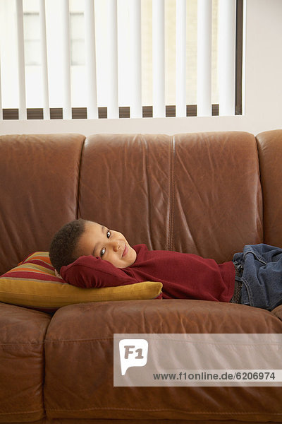 Mixed race boy laying on couch