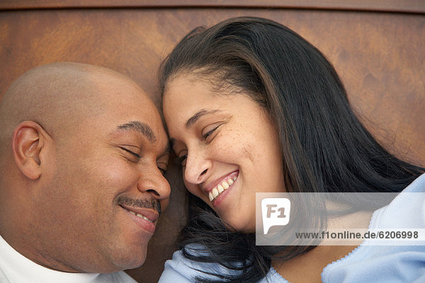 Dominican man lounging in bed with wife