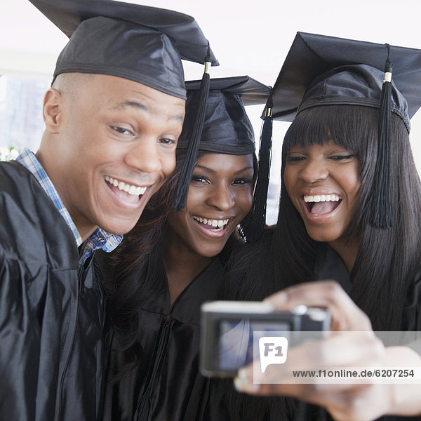 African friends in graduation cap and gown taking self-portrait