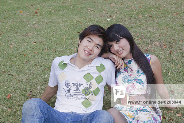 Asian couple sitting in grass together
