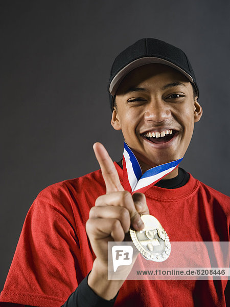 Mixed race baseball player gesturing with award medal