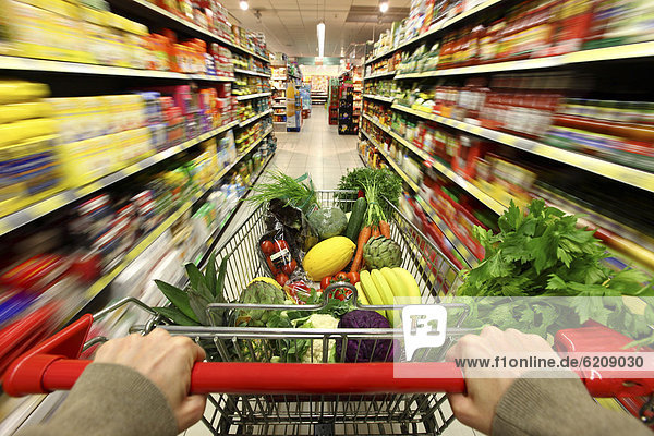 Full shopping trolley being pushed down the aisle  food hall  supermarket  Germany  Europe