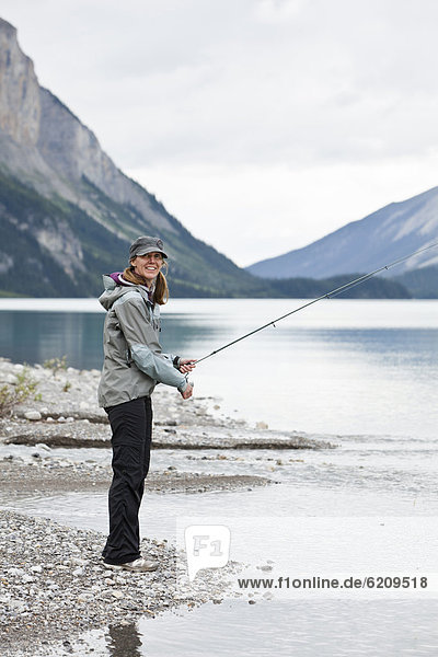 Caucasian woman fishing in Maligne Lake