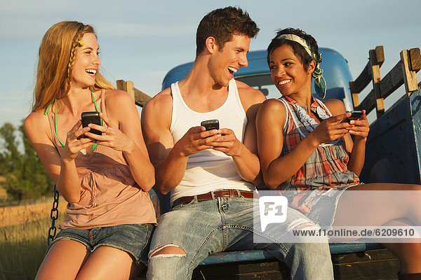 Friends using cell phones in back of truck