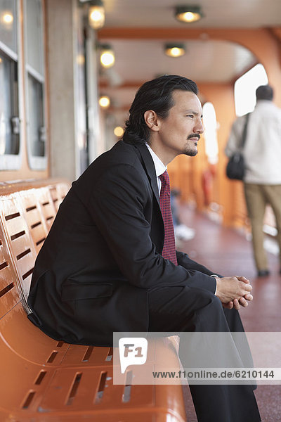 Mixed race businessman on bench and looking pensive