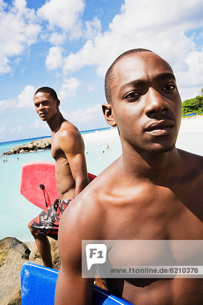 African men holding body boards on beach