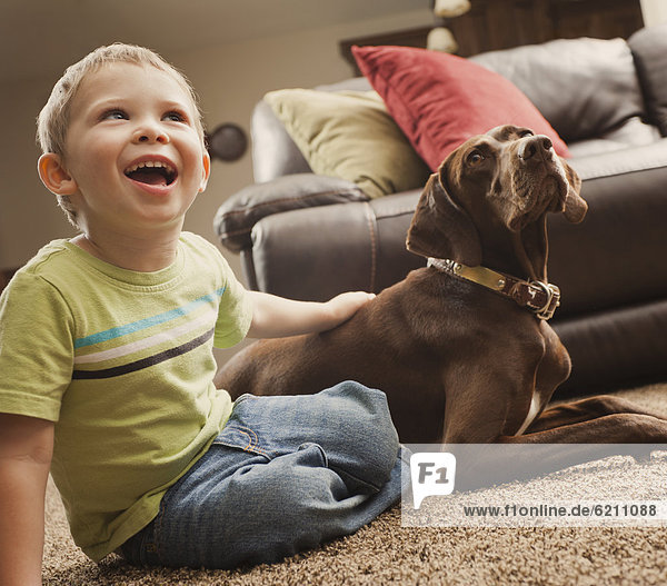 Caucasian boy sitting on floor with dog