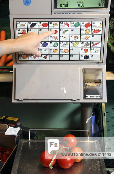 Self-service scales  customer weighing tomatoes  food hall  supermarket  Germany  Europe