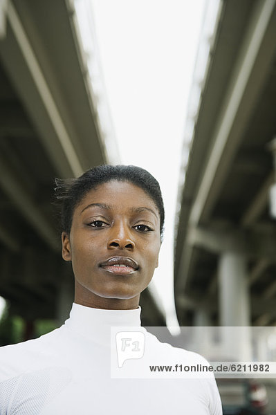 Serious African woman standing under freeway overpass