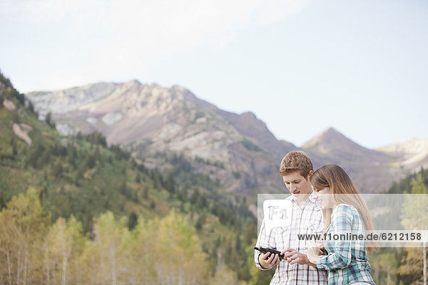 Caucasian couple looking at GPS device in remote area