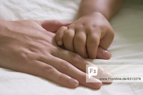 Hispanic mother and baby boy holding hands