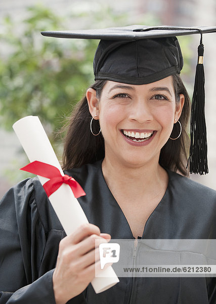 Hispanic graduate holding diploma