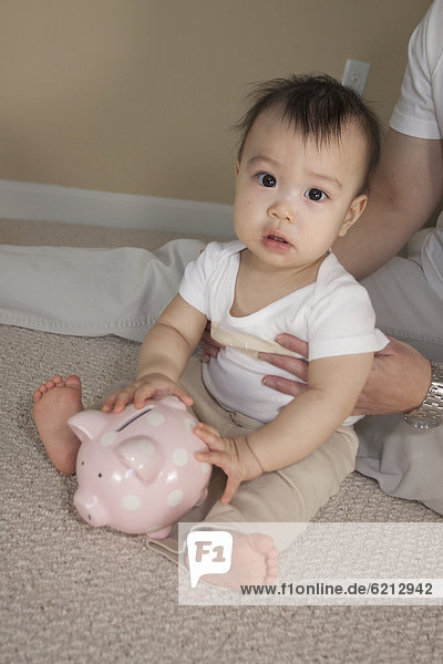 Chinese father and baby with piggy bank