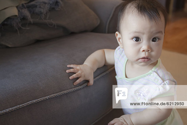 Chinese baby leaning against sofa