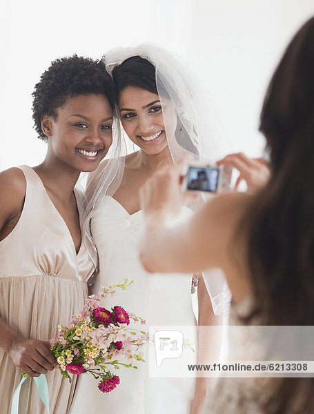 Woman taking picture of bride and bridesmaid