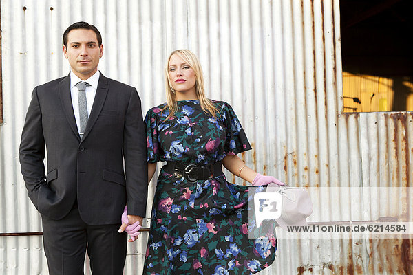 Caucasian couple in elegant clothes standing near wall