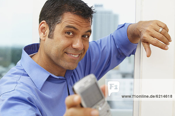 Hispanic businessman text messaging on cell phone