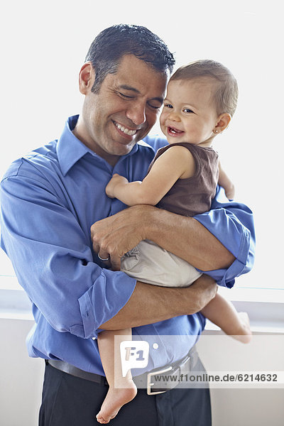 Hispanic father holding daughter