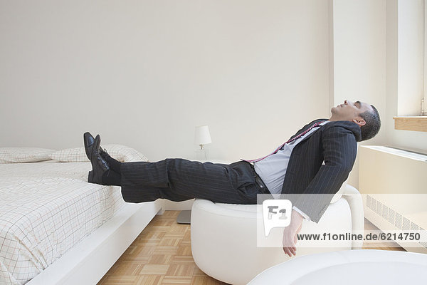 Hispanic businessman napping in chair