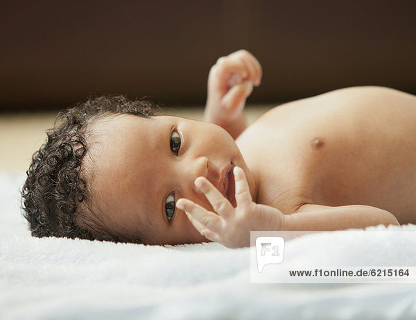 Mixed race newborn baby laying on blanket