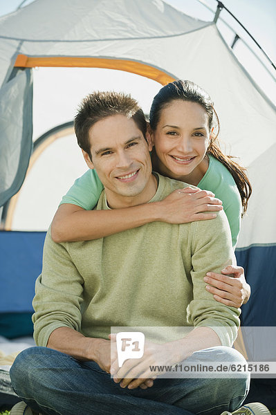 Hispanic couple hugging near tent